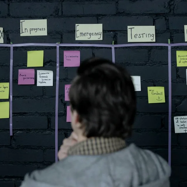 Chef de projet passant en revue un tableau scrum à notes adhésives