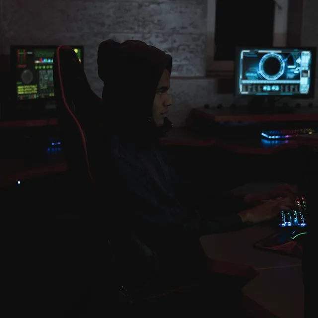 Analyste cybersécurité devant plusieurs écrans dans un SOC sombre