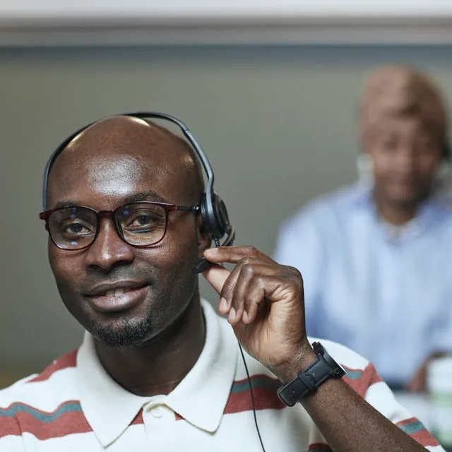 Technicien support souriant au casque en environnement de bureau